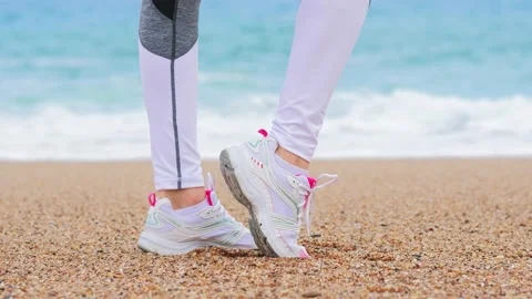 Athletic woman on the beach, warm-up before exercise, getting ready for jogging Stockbeeldmateriaal 134868616