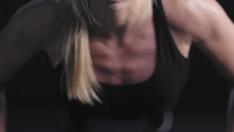 Athletic woman does some push ups, and then takes a break on a dark background Stock Footage 77419560