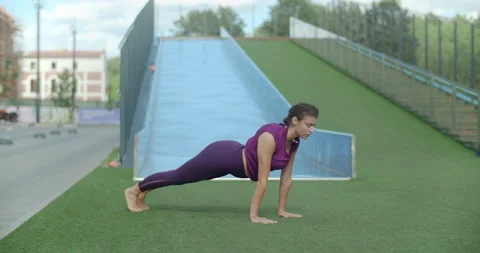 Athletic woman does stretching exercises, warm-up training in the yard of an Stock Footage 139837293