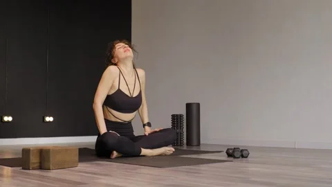 An athletic woman doing neck exercises sitting on a fitness mat. Video stock 304579550