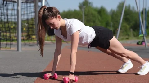 Athletic woman doing a push ups with dumbbells on the playground. Stock Footage 154846171
