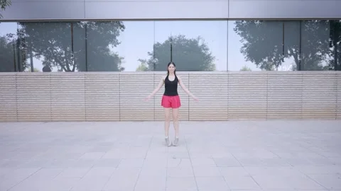 Athletic woman exercising with jumping jacks outside Stockbeeldmateriaal 345083585