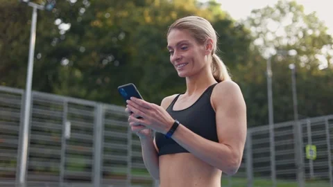 Athletic woman having rest after training and chatting online on smartphone Stock Footage 252199787