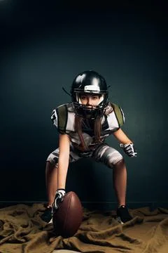 Athletic woman poses in American football uniform with ball in her hand. Stock Photos