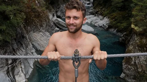 Athletic young guys jumping Into pond from rock cliff slow motion Stockbeeldmateriaal 127842947