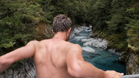 Athletic young guys jumping Into pond from rock cliff slow motion Stock Footage 127843228