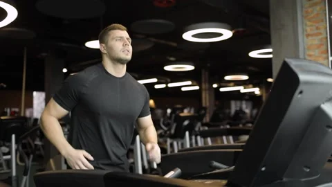 Athletic young man in a black t-shirt is doing cardio exercise on modern Video stock 158724609