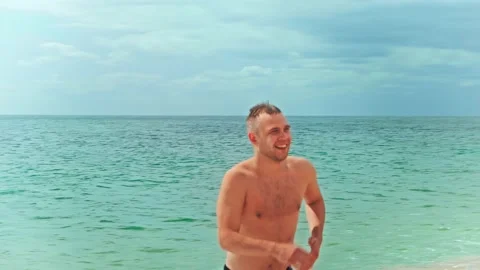 Athletic young man comes out of the sea, smiles and showing thumbs up gesture Stock Footage 194820137