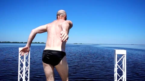 Athletic young man diving into the deep blue water of a lake on a summer Stock Footage 334650425