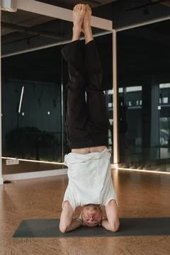 An athletic young man does exercises in the fitness room. A professional guy Stock Photos