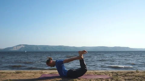 Athletic young man does yoga exercises, seated Forward Bend pose Stock Footage 80793360