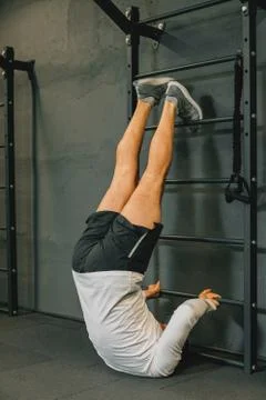 Athletic young man doing exercise for abdomen on vertical bar in gym or fitne Foto stock