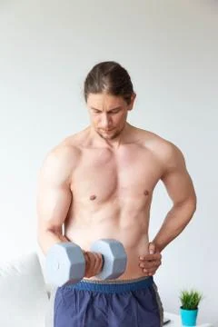 Athletic young man doing exercise with dumbbell in living room at home Stock Photos
