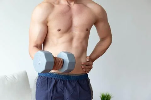 Athletic young man doing exercise with dumbbell in living room at home Stock Photos