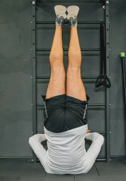Athletic young man doing exercise for abdomen on vertical bar in gym or fitne Stock Photos