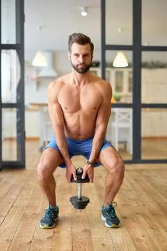 Athletic young man doing exercise with dumbbell at home Stock Photos