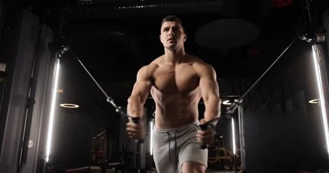 Athletic young man doing exercises for biceps and abs using a modern expander Stockbeeldmateriaal 160028681