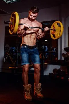 Athletic young man doing exercises with barbell in gym. Handsome muscular bod Foto stock