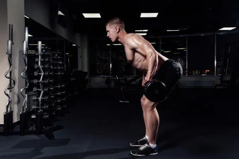 Athletic young man doing exercises with barbell in gym. Handsome muscular bod Foto stock