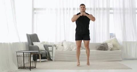 Athletic young man is doing lunge squat exercise in jump in living room at home. Stock Footage 143924785