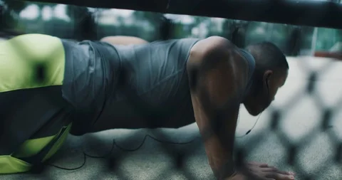 Athletic young man doing push ups while listening to music Stock Footage 85489198