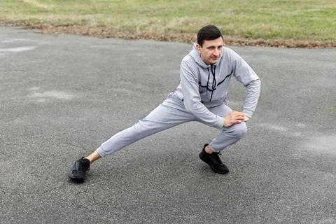 An athletic young man doing side lunges stretching exercise Stock Photos
