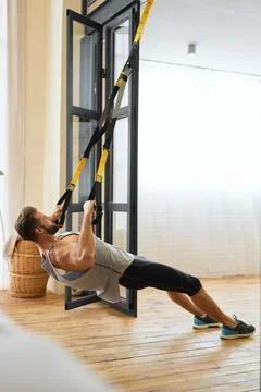Athletic young man doing strength exercise with resistance band Stock Photos