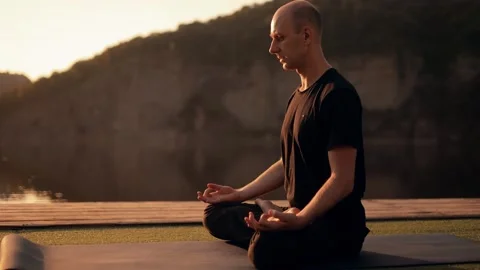 Athletic young man doing yoga on a pier on a river embankment outdoors Stock Footage 246559016