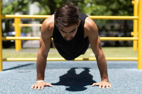 Athletic young man executing a push-up in a park setting Stock Photos