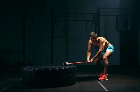 Athletic young man hitting big tire with hummer Stock Photos