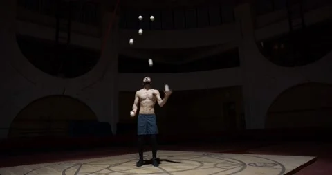 Athletic young man is juggling many balls in a dark arena, circus performer, 4k Stock Footage 147192029