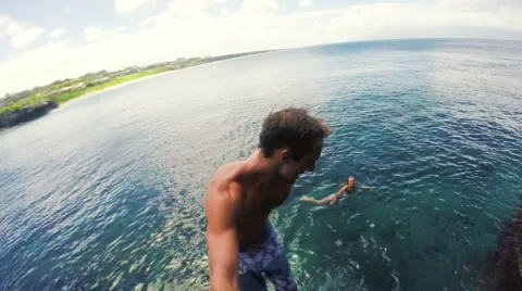 Athletic Young Man Jumping From Cliff Into Ocean Sea Water Muscular Adventure Stock Footage 55336128