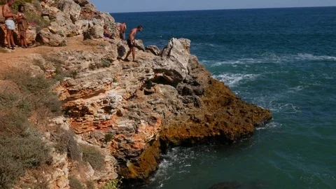 Athletic Young Man Jumping From Cliff Into Ocean Sea Water Video stock 79471726