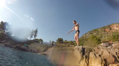 Athletic Young Man Jumping From Cliff Into Ocean Sea Water Muscular Adventure Stock Footage 80254081