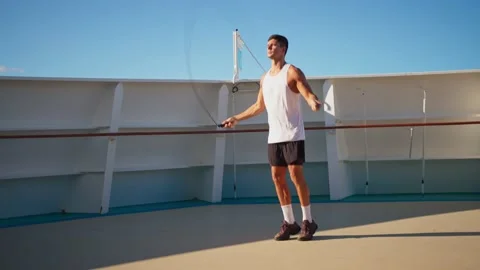 Athletic young man jumping rope outside on cruise ship open deck Stock Footage 194440333