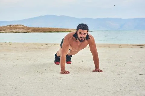 Athletic young man posing on the beach Stock Photos