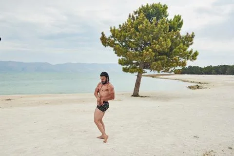 Athletic young man posing on the beach Stock Photos