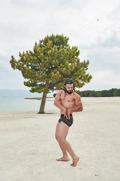 Athletic young man posing on the beach 스톡 사진