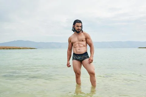Athletic young man posing on the beach 스톡 사진