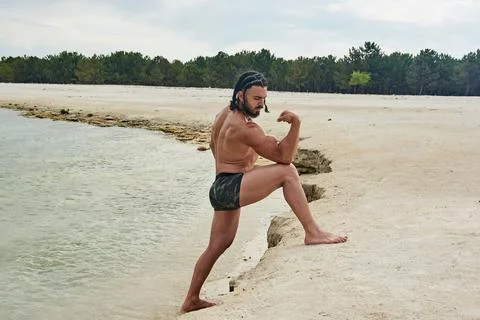 Athletic young man posing on the beach Stock Photos