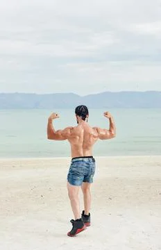 Athletic young man posing on the beach Stock Photos