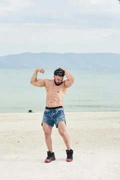 Athletic young man posing on the beach 스톡 사진
