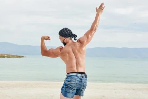 Athletic young man posing on the beach Stock Photos