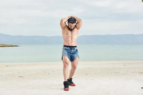 Athletic young man posing on the beach Stock Photos