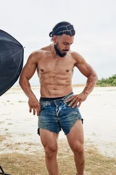 Athletic young man posing on the beach Stock Photos