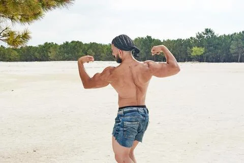 Athletic young man posing on the beach 库存照片