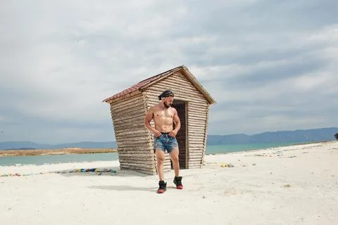 Athletic young man posing on the beach Stock Photos