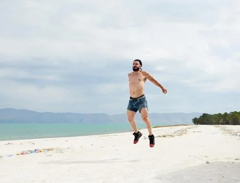 Athletic young man posing on the beach Stock Photos
