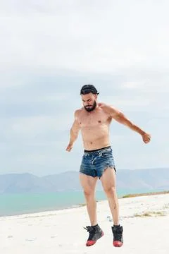 Athletic young man posing on the beach Stockfoto's