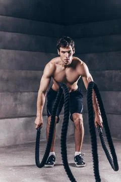 Athletic young man with rope doing exercise in functional training fitness gy Stock Photos